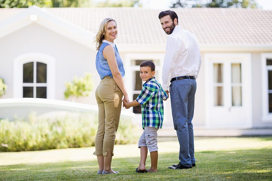Personal Insurance - Happy Parents and Son Standing in the Garden in Front of Their Newly Purchased Home on a Bright Sunny Day